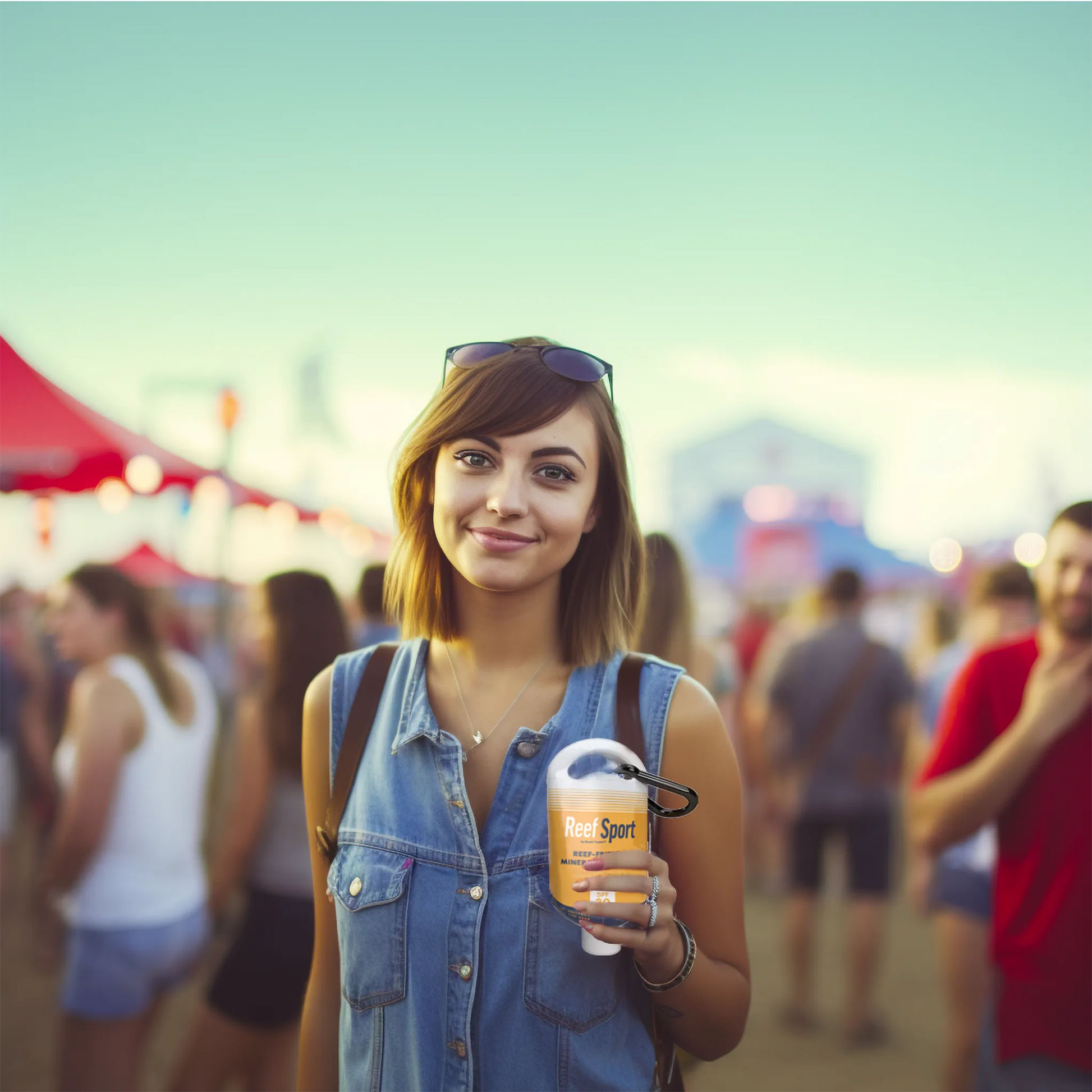 Young woman at outdoor event holding XL hidden sunscreen flask with carabiner, ideal for concerts and tailgates.